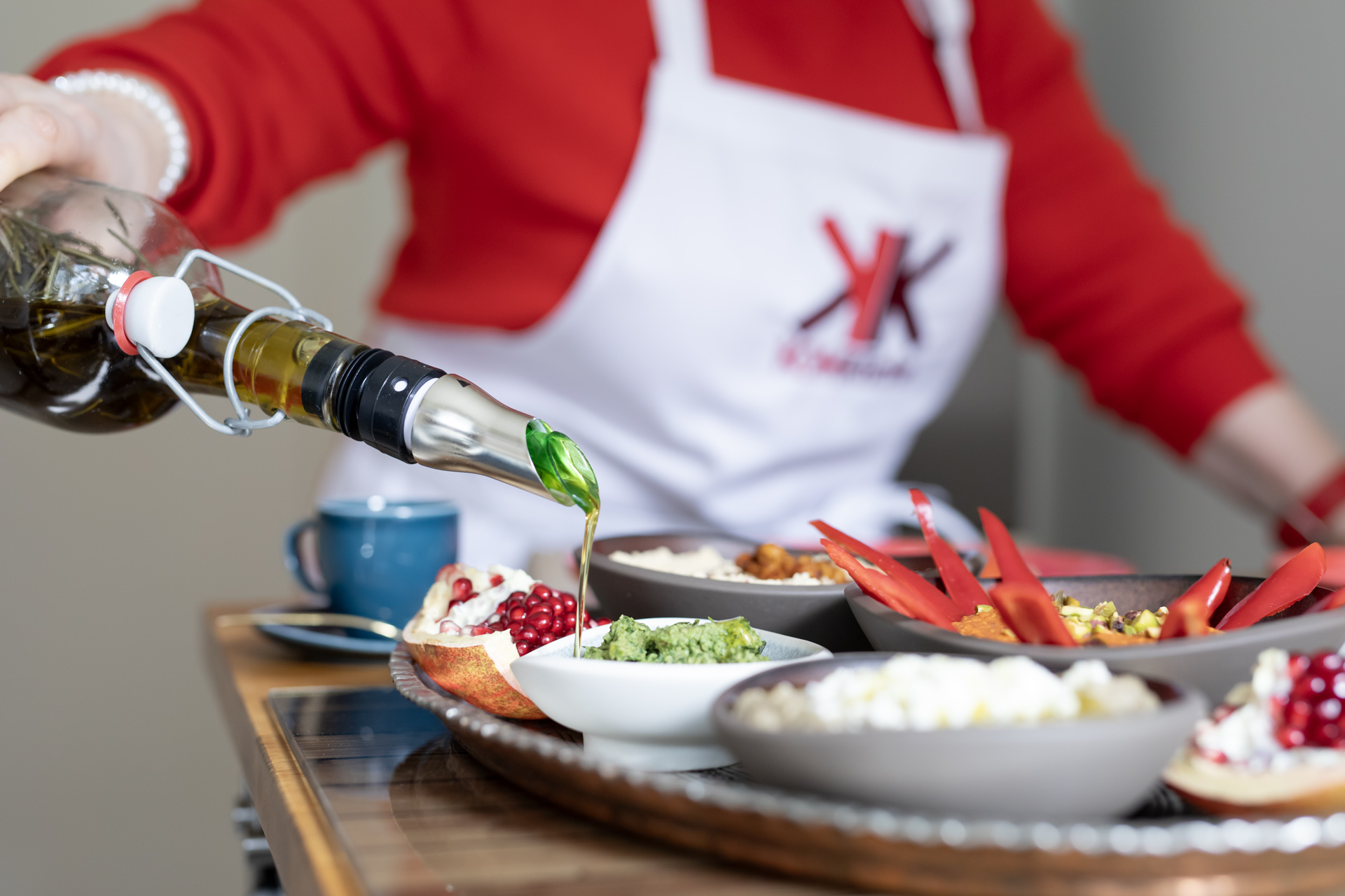 KOMKüche Markenberatung in Mannheim: Yeliz Kavak-Küstner gießt Olivenöl über eine mediterrane Speise und verfeinert damit die Markenarbeit ihrer Kunden.